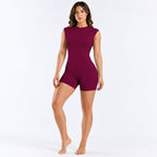 A woman modeling a sleeveless, bodycon short romper in deep burgundy against a clean white studio background.