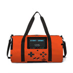 An orange duffel bag designed to look like a retro handheld game console, featuring black handles and straps, with a screen displaying 'START GAME'.