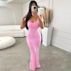 Woman in a pink strapless dress taking a mirror selfie in a minimalistic room.