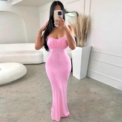 Woman in a pink strapless dress taking a mirror selfie in a minimalistic room.