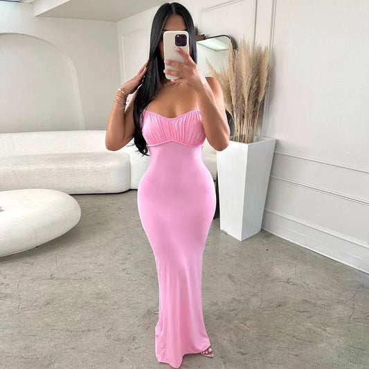 Woman in a pink strapless dress taking a mirror selfie in a minimalistic room.