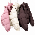 Three puffer jackets hanging side by side on a white background: one dusty pink, one cream, and one dark brown.